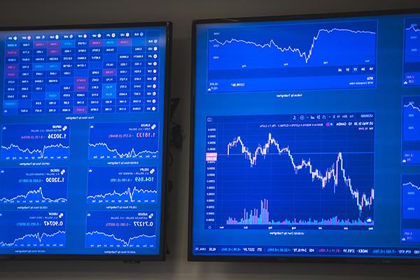 两个显示器显示股票市场和金融图表
